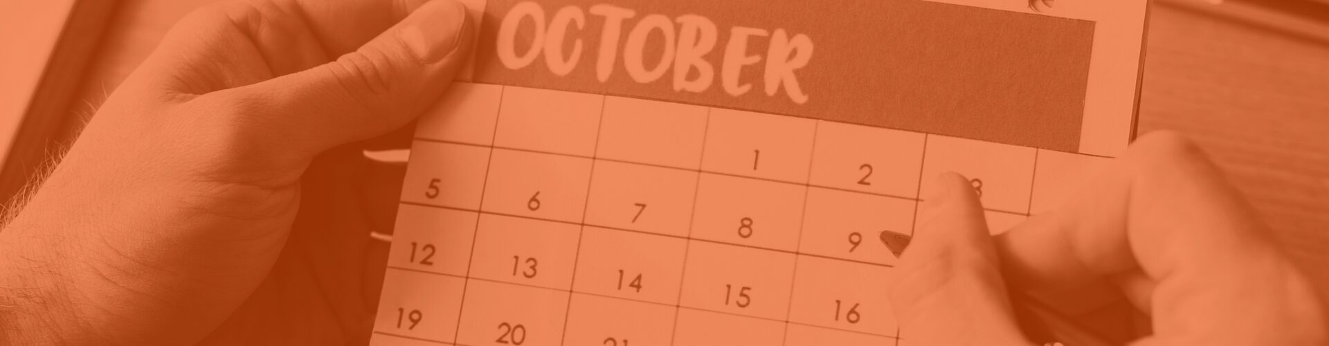 Kalenderblatt Oktober, eine Hand markiert mit einem Stift die Tage 5 bis 9